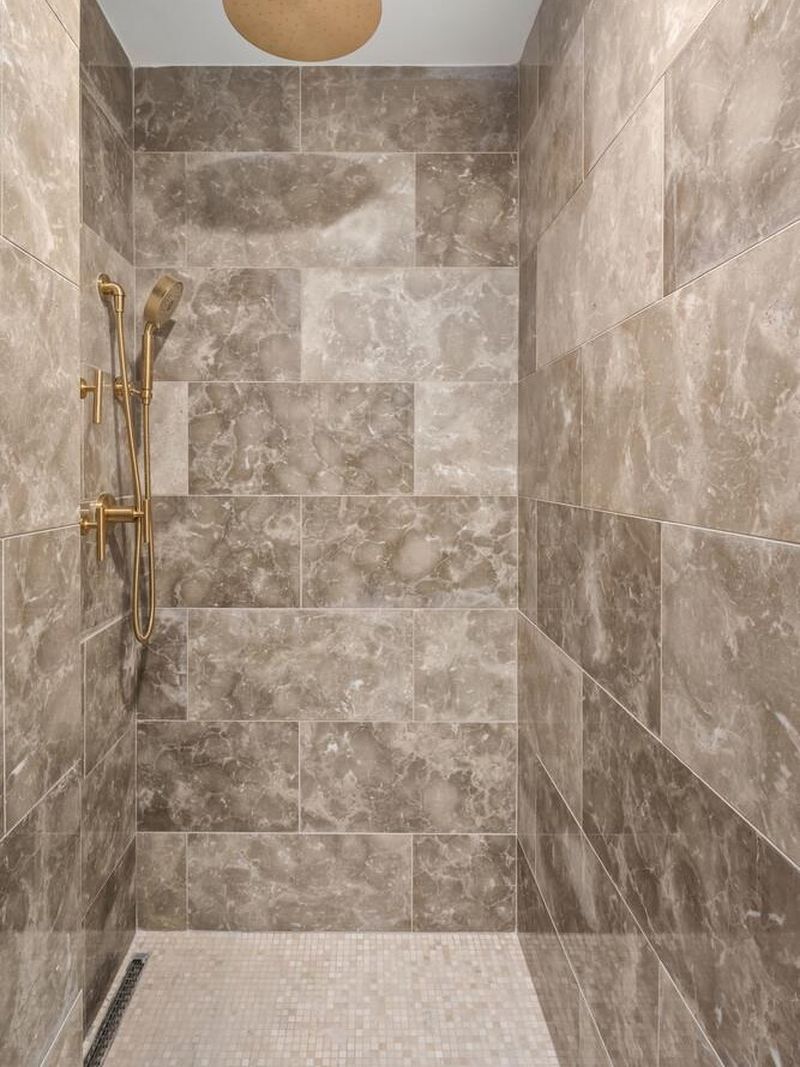 Stone-clad walk-in shower with brass fixtures at 1200 Fifth Avenue 15A, Carnegie Hill — photo 7 of 13