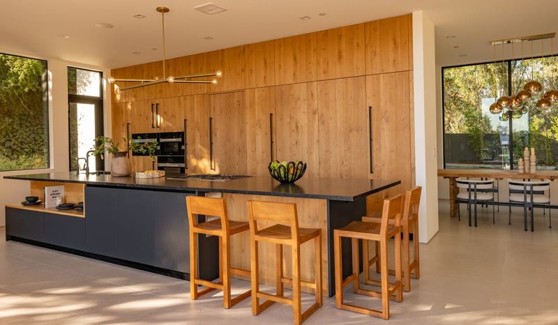 Chef's kitchen with dark stone island and warm wood cabinetry at 12752 Mulholland Drive, Beverly Hills — photo 6 of 8