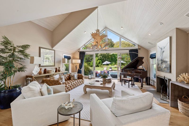 Living room with cathedral ceiling, piano and pool views at 2 Borden Lane, East Hampton — photo 4 of 12