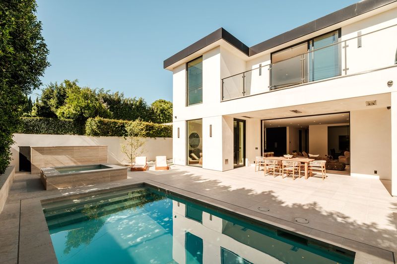 Saltwater pool and limestone terrace behind the contemporary facade at 317 South Wetherly Drive, Beverly Hills