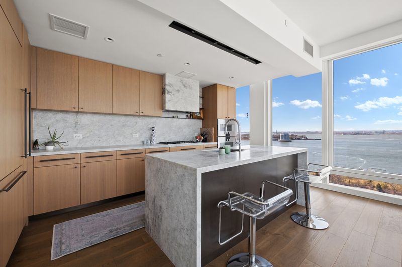 Kitchen with large center island, white oak cabinetry and water views at 50 Bridge Park Drive 16B, Brooklyn Heights — photo 3 of 12