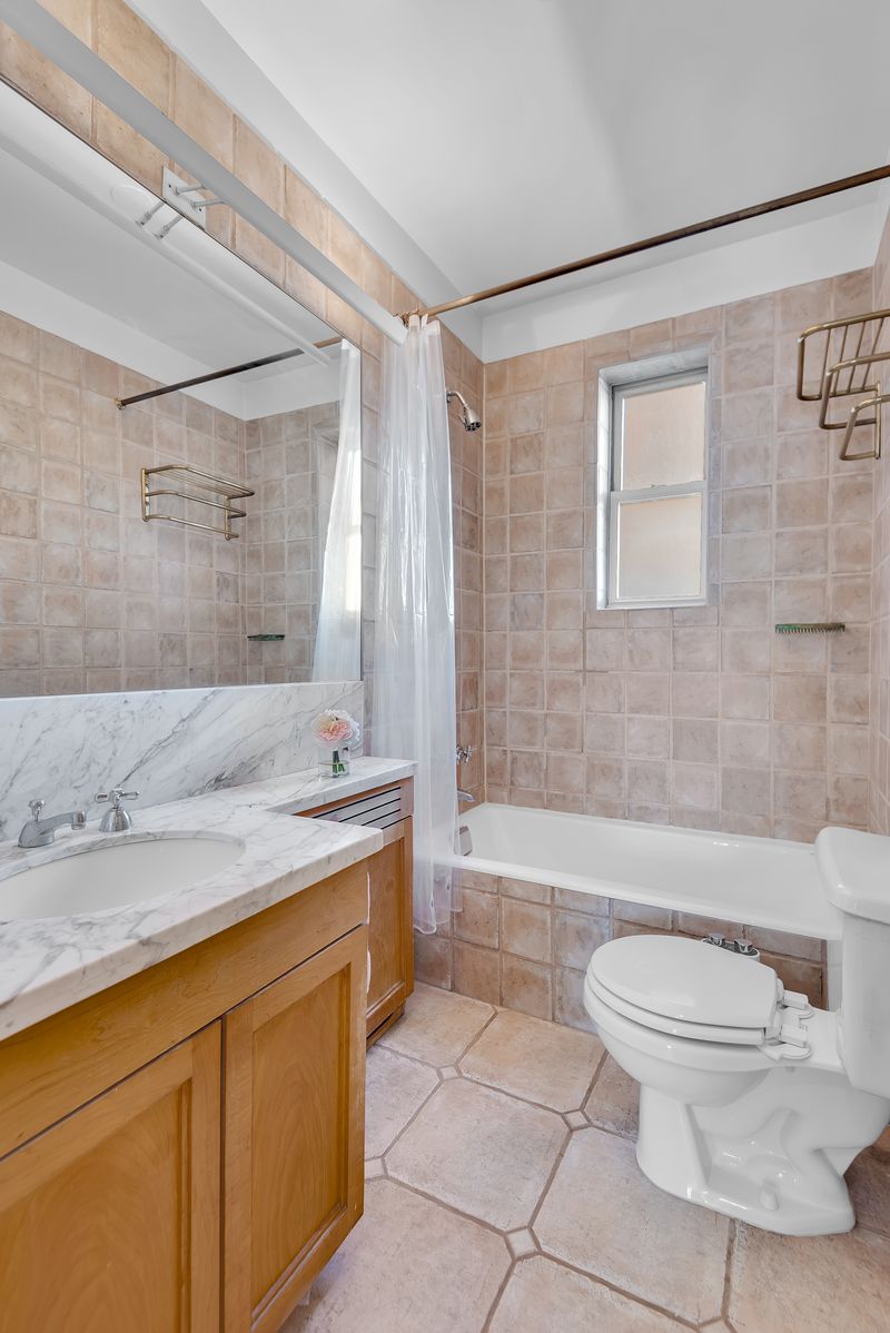 Bath with a tub and marble-top vanity at 55 East 86th Street 8B, Carnegie Hill — photo 8 of 9