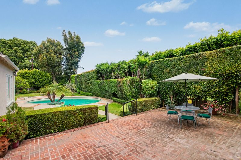 Brick patio and pool framed by tall hedges at 608 Trenton Drive, Beverly Hills Flats — photo 2 of 10